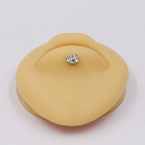 Macro detail of cat paw navel ring with silver plating and clear cubic zirconia stones