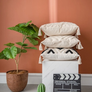 Moroccan tufted pillows with tassels on marble stand against terracotta wall background