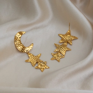 Detail view of vintage-style asymmetrical hammered gold star and moon earrings on silk