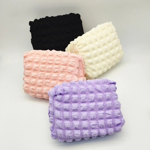 Quilted seersucker makeup bags in four colors with textured bubble fabric and zipper closure