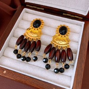 Detail of vintage gold fan earrings with black stone and brown wooden beads in a box