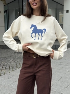 Primer plano del estampado de caballo azul en sudadera crema de manga larga