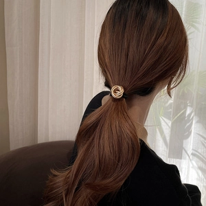 Close-up of golden metal knot hair tie worn on hair in a soft minimalist setting