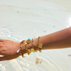 Gros plan de bracelets en acier doré 18 carats avec perles et breloques dans l'eau