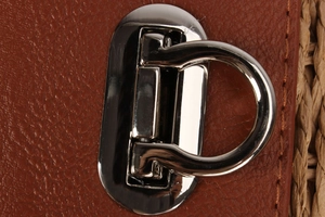 Detailed view of polished silver metal twist lock on dark brown lychee leather straw bag
