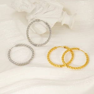 Detail view of twisted gold and silver hoop earrings on a luxury white art background