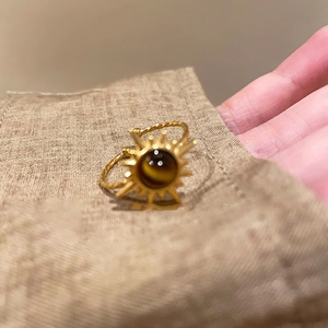 Detail of bohemian sun ring with brown tiger eye stone and golden twisted band
