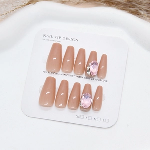 Pink press-on nails with luxury rhinestones and pearls in long coffin shape on display