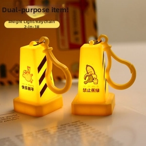 Close-up of yellow traffic cone keychain featuring LED light and creative cartoon print
