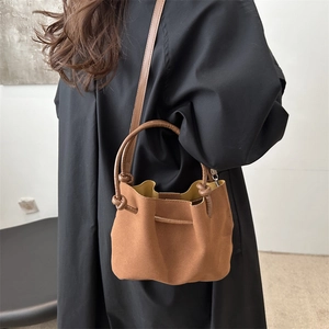 Brown faux suede bucket tote bag with drawstring closure shown on model in studio