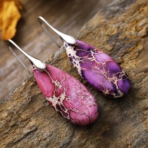 Detail of purple imperial stone teardrop earrings on a natural brown rock background