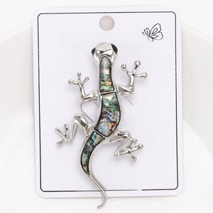 Detail of silver gecko brooch with colorful abalone shell inlay on display card