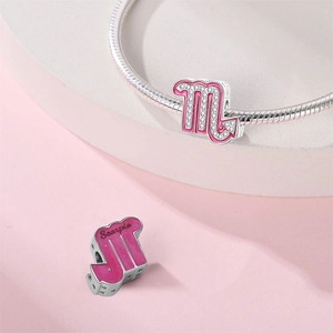 Macro detail of silver Scorpio charm with pink enamel and sparkling zircon on snake chain