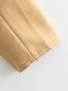 Macro detail of camel suede fabric texture with raw cut edges and decorative stitching