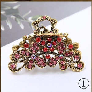 Retro bronze metal hair claw clip with pink and red rhinestones on white background