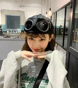 Detail shot of black aviator goggles baseball cap worn by a model in industrial setting