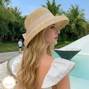 Elegant beige woven straw sun hat with pink ribbon bow detail for summer beach vacation