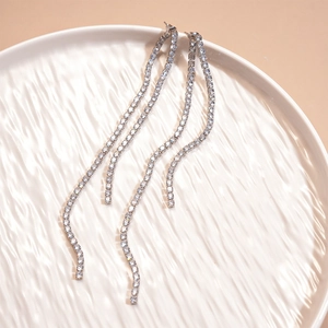 Detail of silver long tassel earrings with sparkling zircons on white ceramic plate