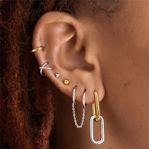 Detailed close-up showing gold and silver mixed metal earrings on a model ear