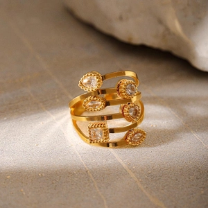 Gros plan d'une bague spirale dorée sertie de zircons variés sur une pierre texturée