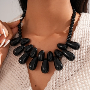 Statement chunky black acrylic necklace with teardrop pendants on a beige sweater