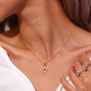 Détail du collier doré avec pendentif en étoile serti d'une pierre œil de chat sombre