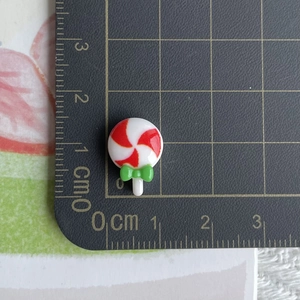 Mini resin lollipop ornament with green bow measured on a metric cutting mat