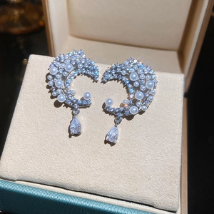 Macro shot of silver crescent moon earrings with inlaid pearls and zircon pendants