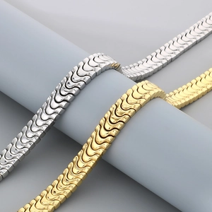 Polished silver and gold dragon bone link chains draped over a gray cylindrical display