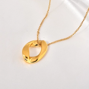 Détail d'un pendentif ovale torsadé doré avec un petit zircon sur fond en satin blanc