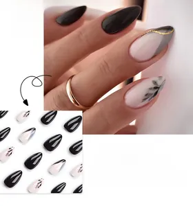 Détail de faux ongles longs pointus avec motifs à l'encre noire et accents dorés