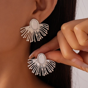Close-up of silver earrings featuring a radial texture and oval opal-like gemstone