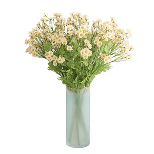 Artificial chamomile daisies in a green glass vase for home and table decoration