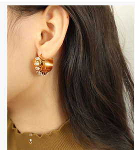 Detailed view of gold C-shaped earring with cubic zirconia crystals on model's ear