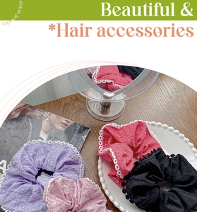 Detailed view of lace hair scrunchies in purple, pink, magenta, and black on a wooden table