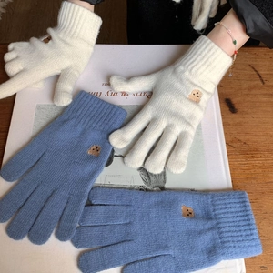 Close-up of knit gloves with bear embroidery and elastic ribbed cuffs in soft winter colors