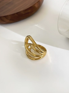 Polished 18K gold multilayer wave ring displayed on a clean minimalist surface