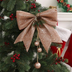 Champagne gold Christmas tree bow with pine cones and hanging ornaments on green branch