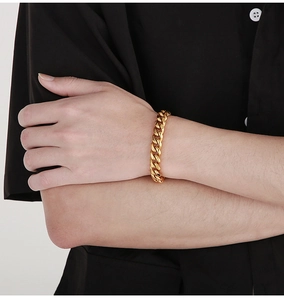 Detailed close-up of a 10mm golden Cuban link chain bracelet on a model wrist