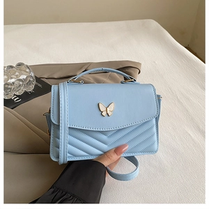 Detail of light blue quilted leather bag featuring a butterfly clasp and top handle
