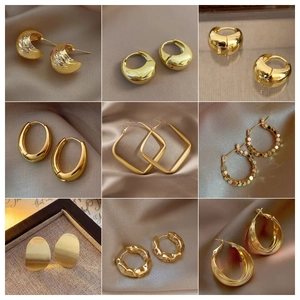 Detailed collection of nine vintage gold-plated geometric earrings on silk background