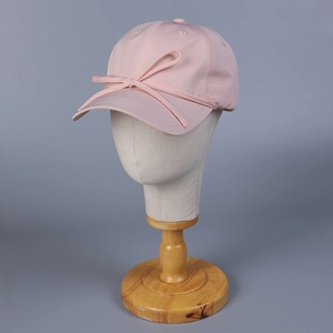 Close-up of pink satin baseball cap with a sweet decorative bow on a display head
