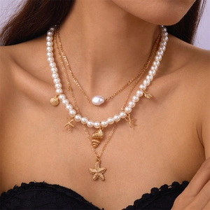 Detail of layered gold necklace with white pearls, shell and starfish pendants on model