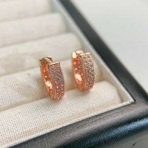 Macro shot of rose gold hoop earrings featuring three rows of micro-pave white zircons