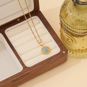 Close-up of a gold necklace with turquoise sunburst pendant in a luxury wooden jewelry box