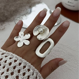 Three-piece matte silver rings set including floral and pearl designs worn by a model