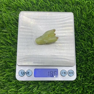Green natural stone dragon head carving on digital scale weighing 18.6 grams