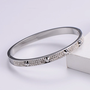 Macro detail of silver nail bracelet featuring sparkling pavé crystals and metallic rivets