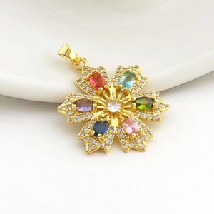 Exquisite gold floral pendant with colorful zircon stones on a white ceramic tray