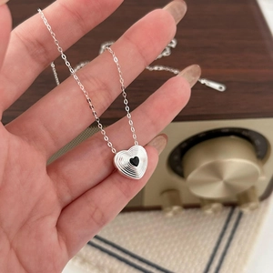 Minimalist 925 sterling silver heart necklace with black gemstone pendant shown by hand